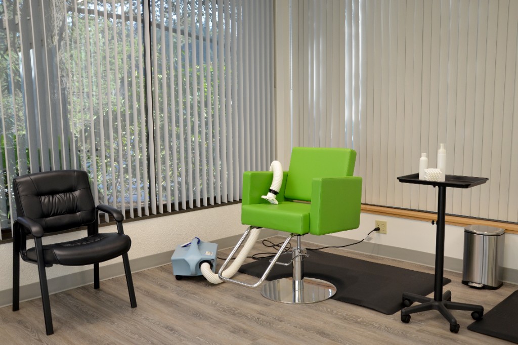 A treatment station with a green styling chair and the AirAllé device.